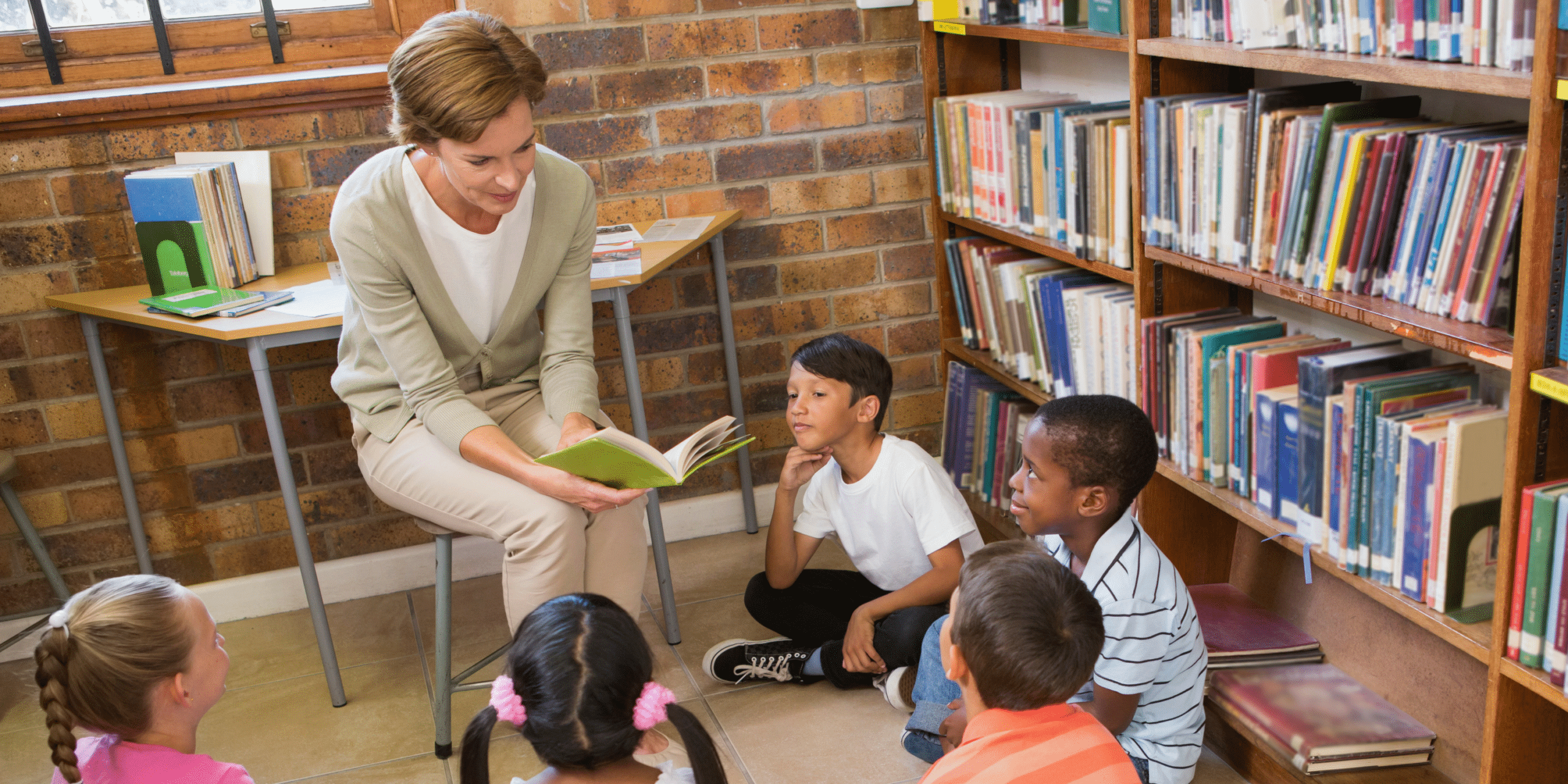 a teaching assistant reads to a class of young children