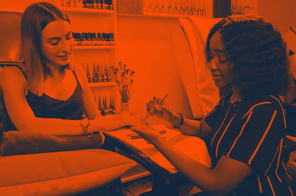 A woman paints another woman's nails at a beauty salon