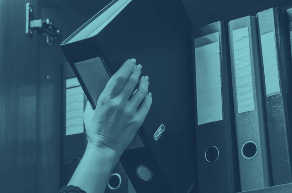 Woman lifting a folder from a shelf