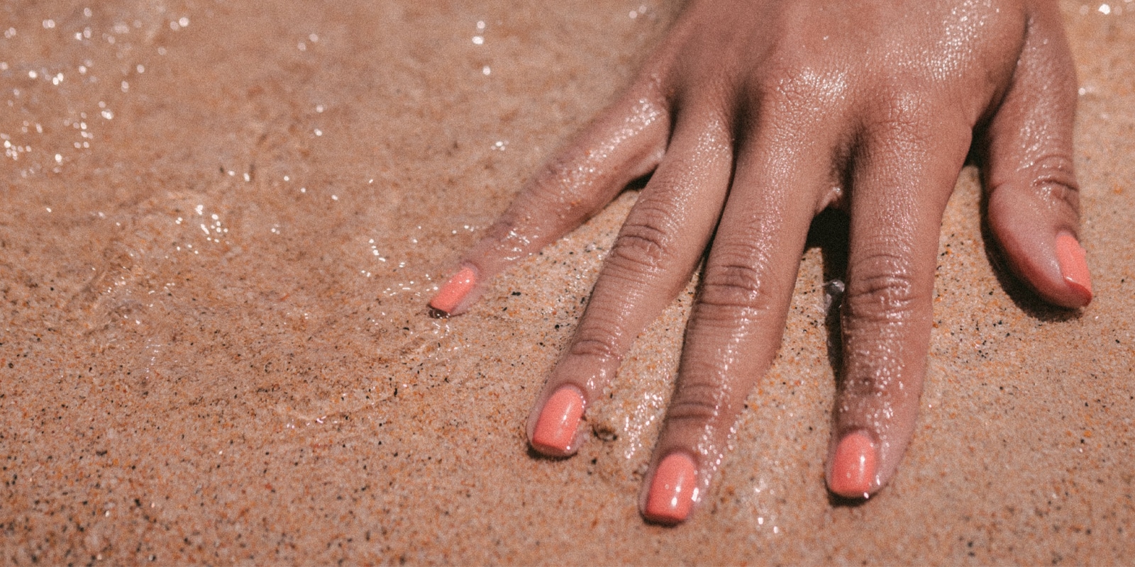 An image of a woman's hand covering in sand