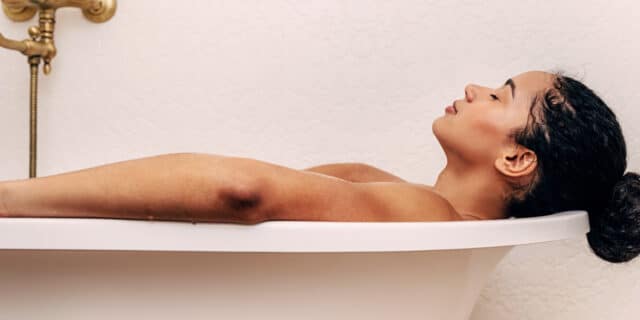 An image of a woman laying in a bathtub with her eyes closed