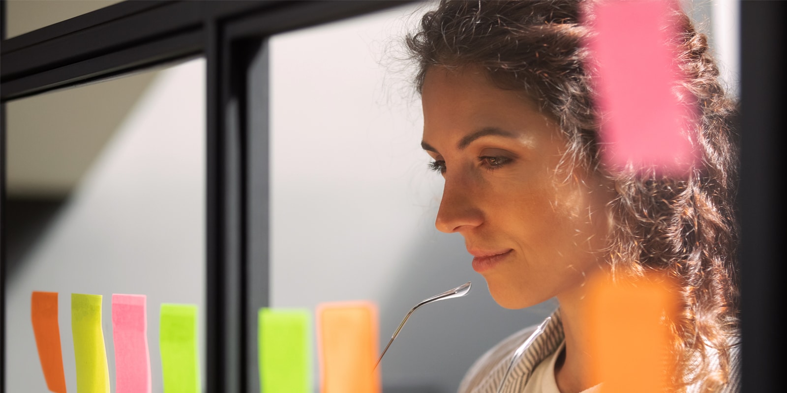 An image of a woman looking at post-it notes and under deep contemplation