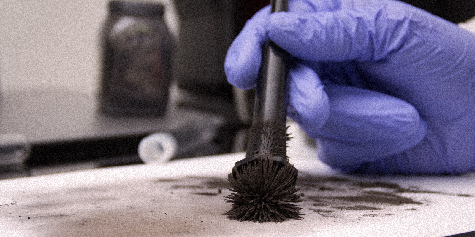 An image of a forensic scientist brushing for prints