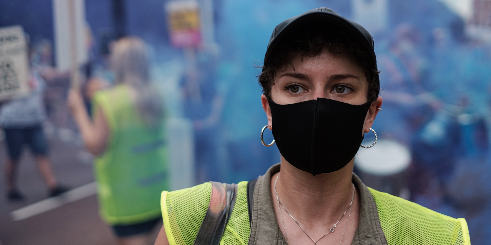 An image of a protest with a woman portrait covering her face with a mask