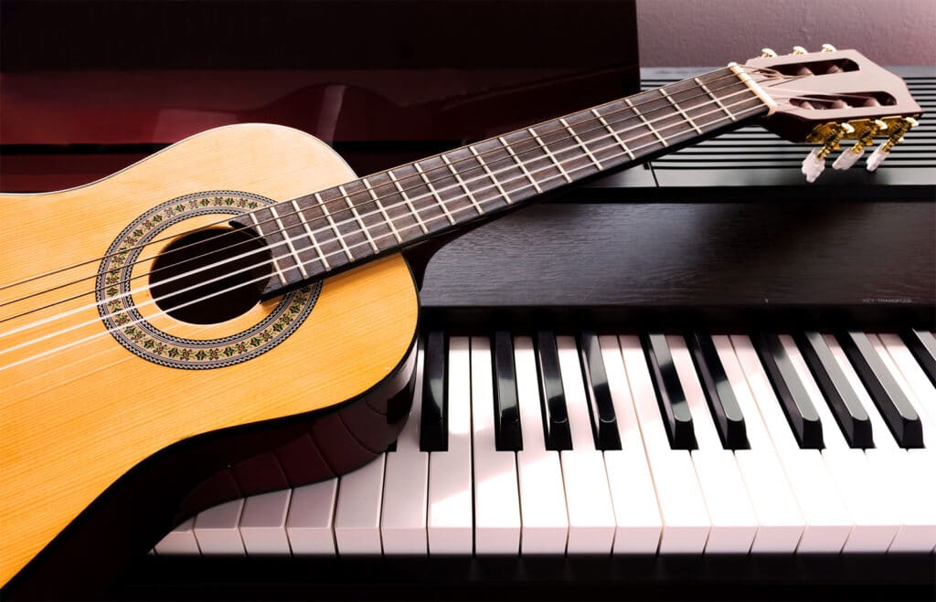 Piano with a guitar resting on it.