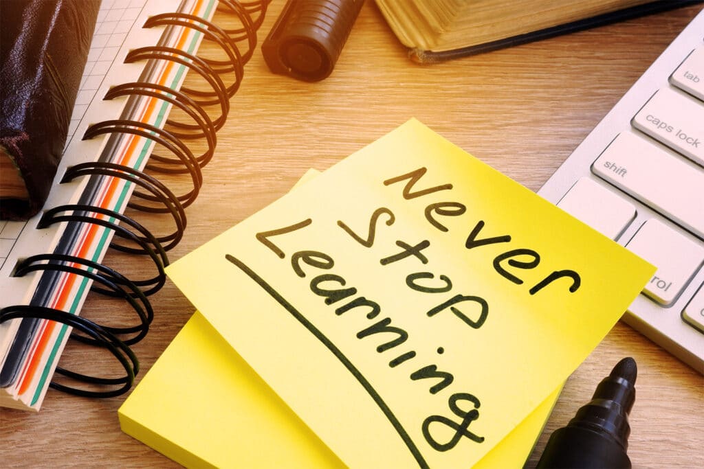 A post-it note on a desk that says 'Never stop learning'.