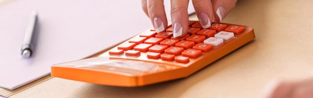 a woman types on an orange calculator