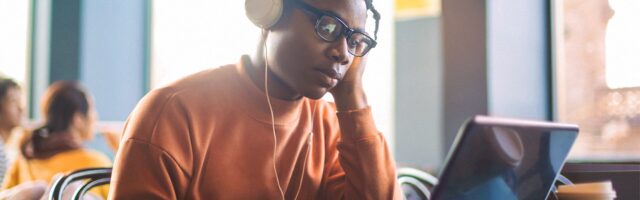 a young student wearing headphones focusses whilst learning online