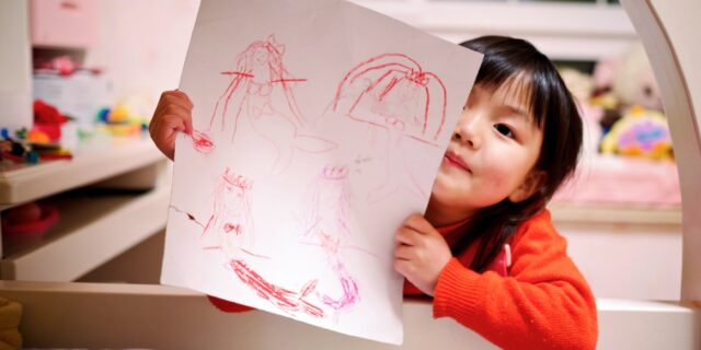 a young child shows off a drawing