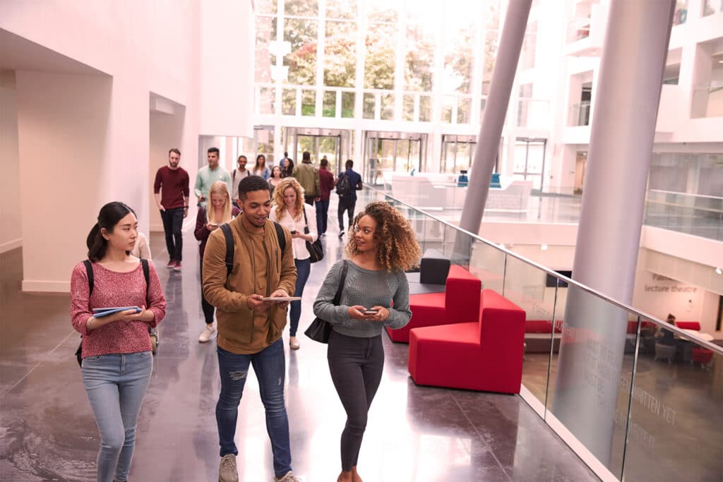 Students at russell group universities
 using their mobile phones and walking through a lecture building.
