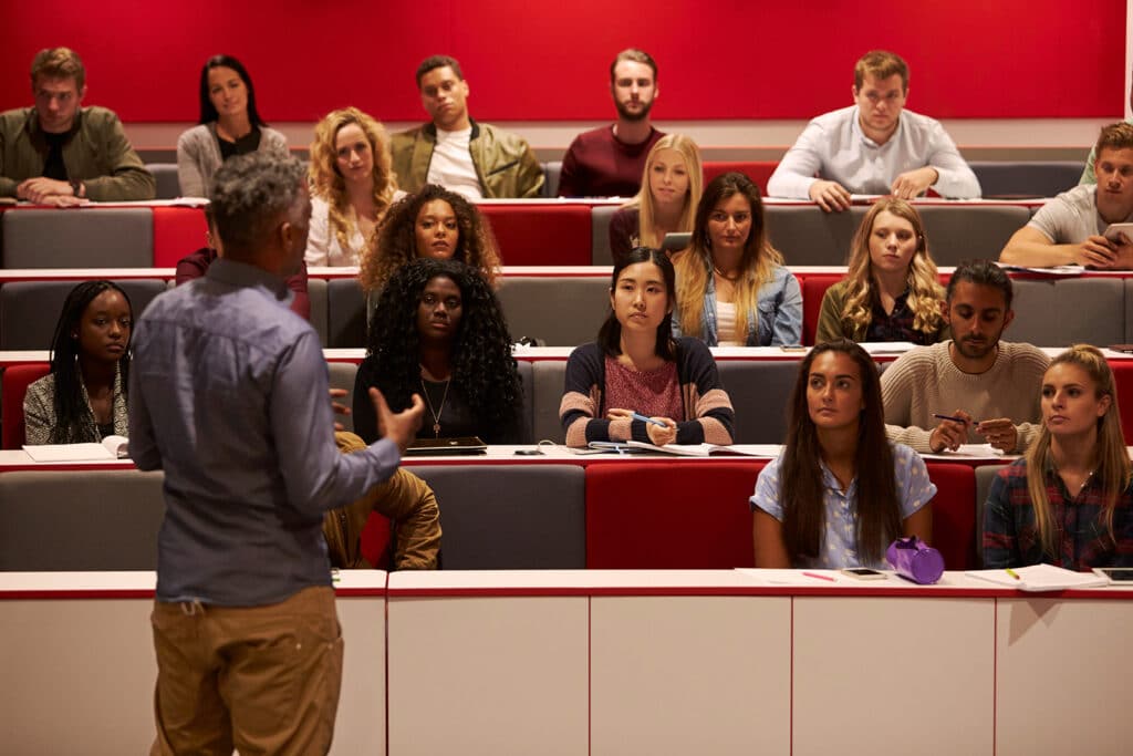 A lecturer speaking to a group of people in a small lecture room, explaining What is a Russell Group University.