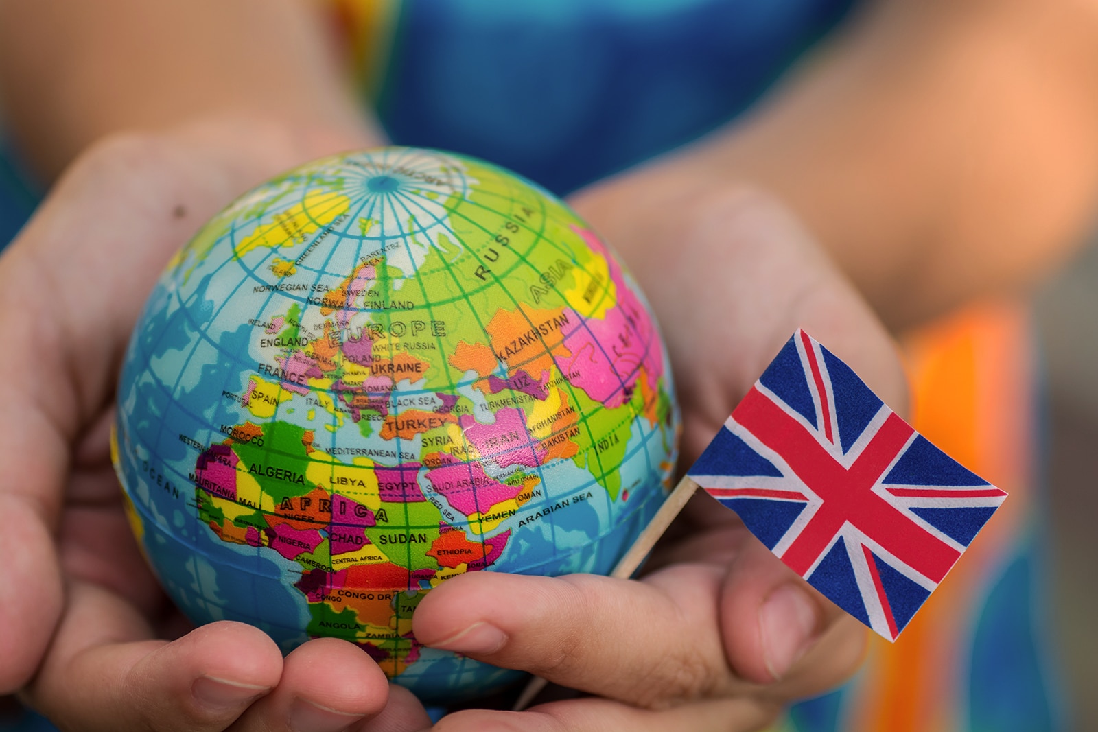 Hands holding a mini globe and small union jack