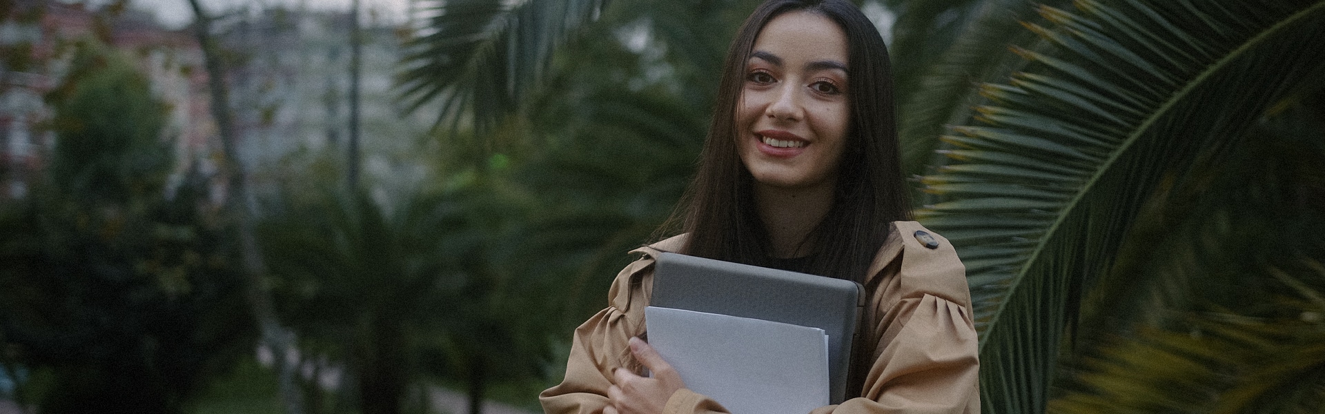 A student holding a laptop and papers