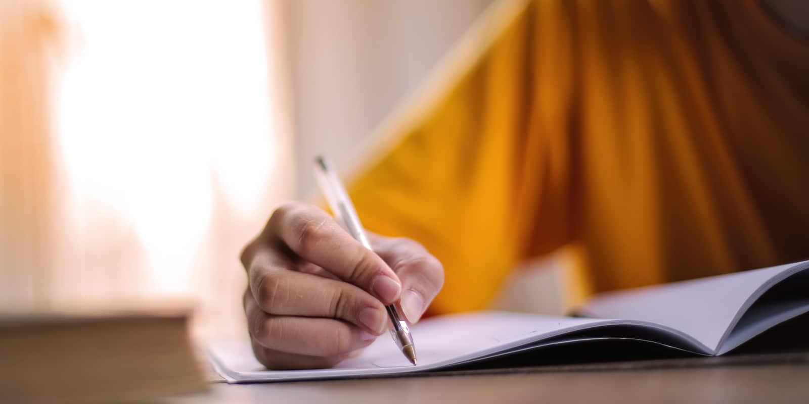 a young woman in a yellow sweatshirt makes notes