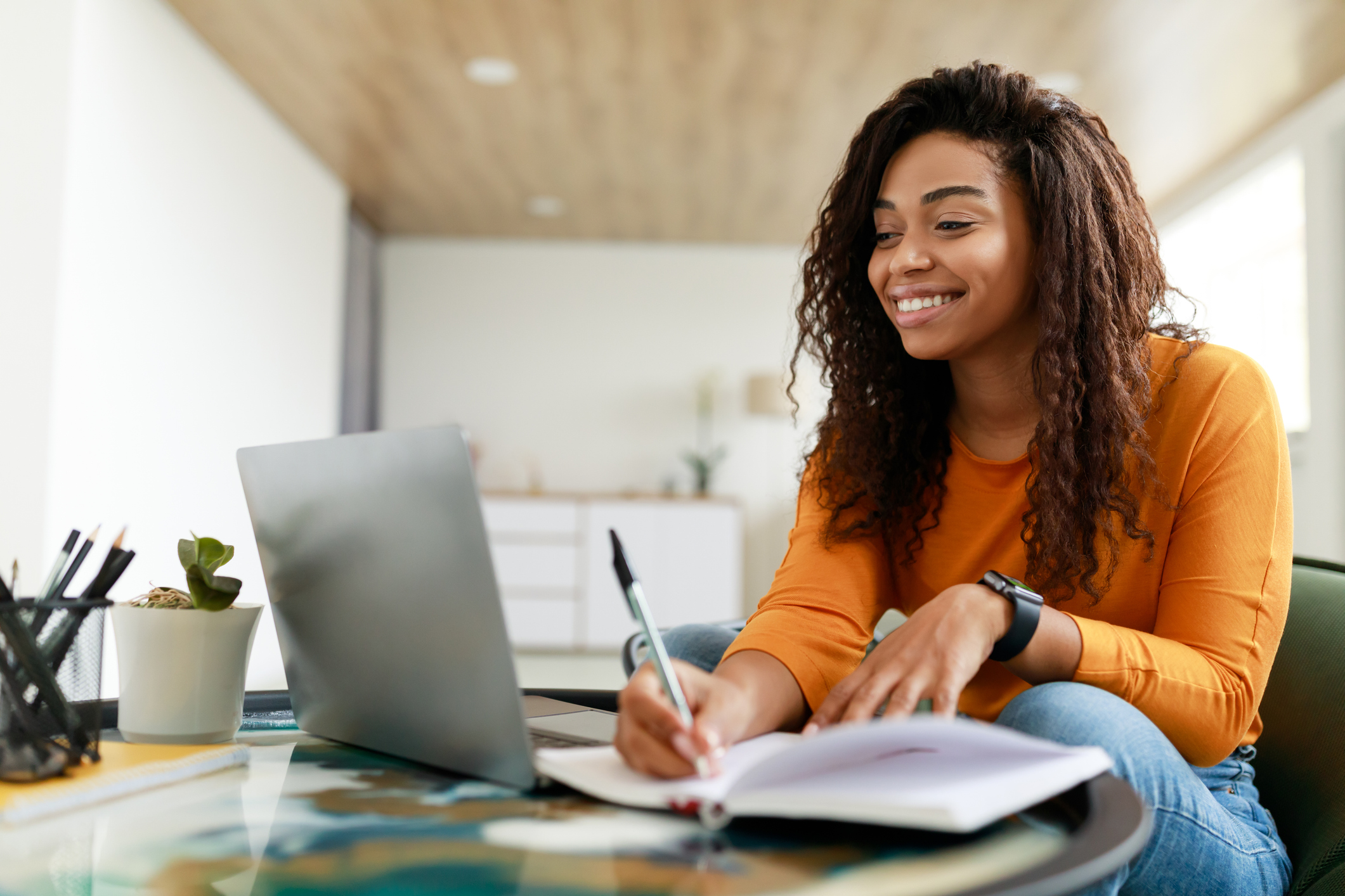 A woman studying from home using her laptop and notebook