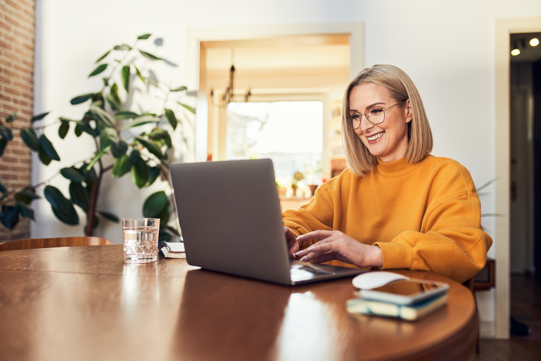 A happy woman sat at her laptop whilst learning from home