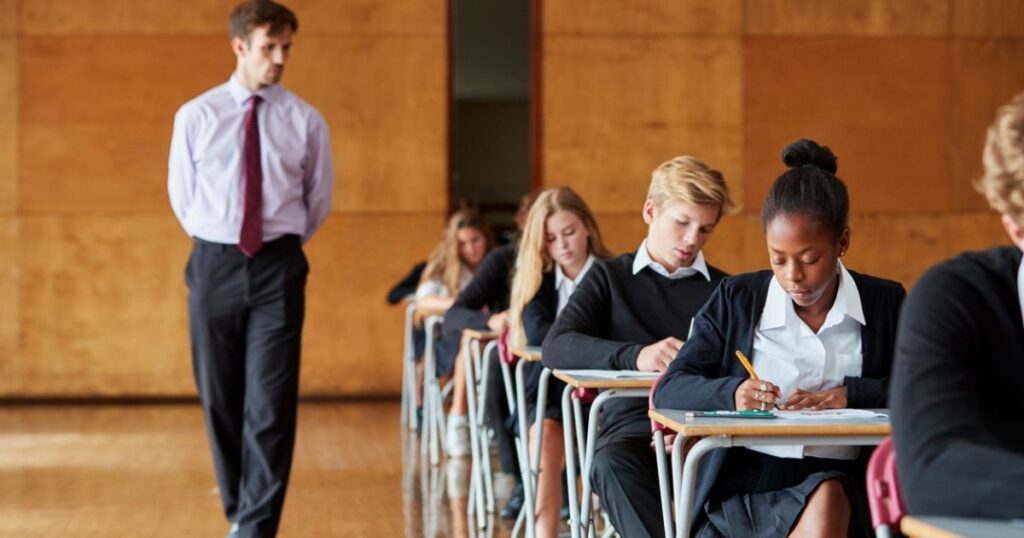 A-level students sitting their exams whilst being monitored by a teacher