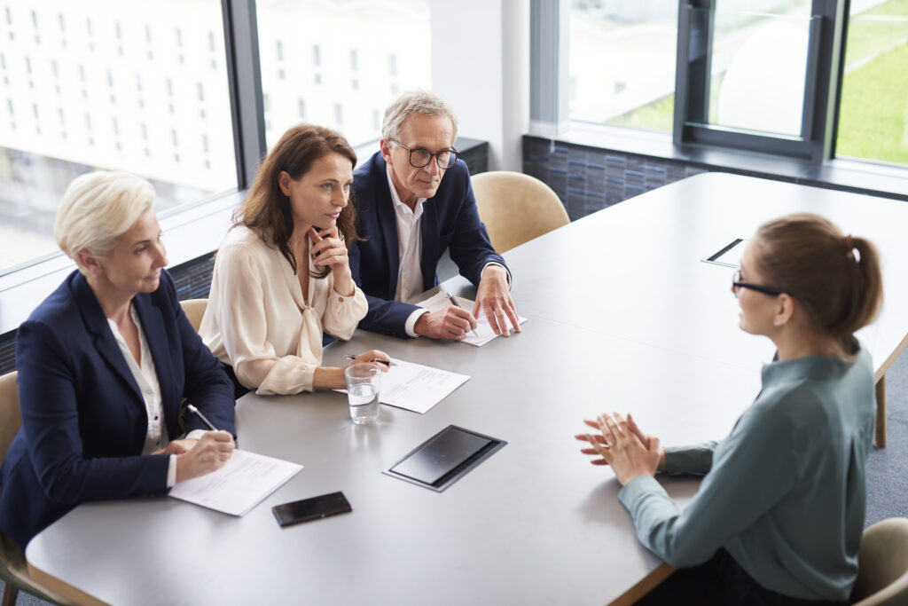 Woman during job interview and three elegant members of management