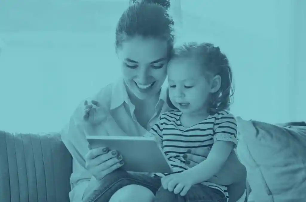 woman looking at tablet with young child